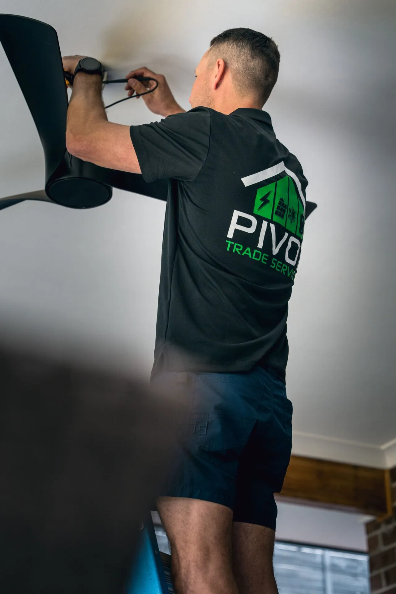 Pivot Trade Services electrician mounting a ceiling fan to a plasterboard ceiling