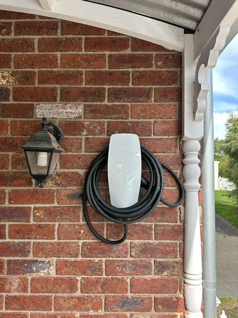 Home EV charger installed on a red brick wall beside a coach light