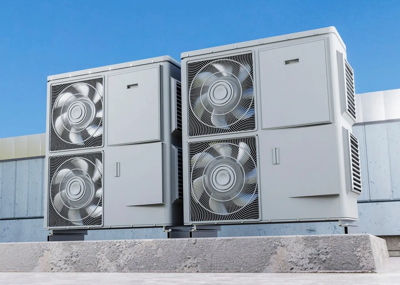 Close-up of a heat pump outdoor unit mounted on a brick wall above a lawn