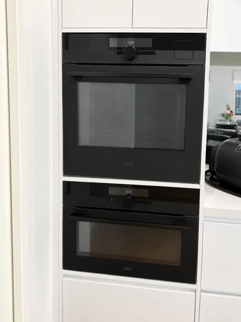 Built-in double oven installed in a white kitchen cabinetry tower